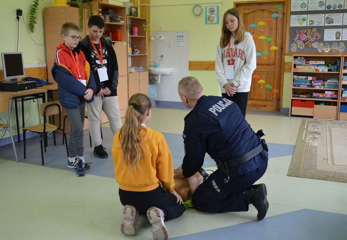 policjant tłumaczy dzieciom zasady pierwszej pomocy
