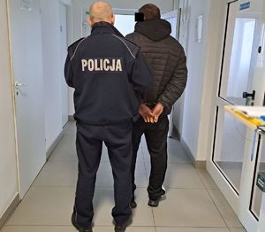 policjant prowadzi w komendzie zatrzymanego